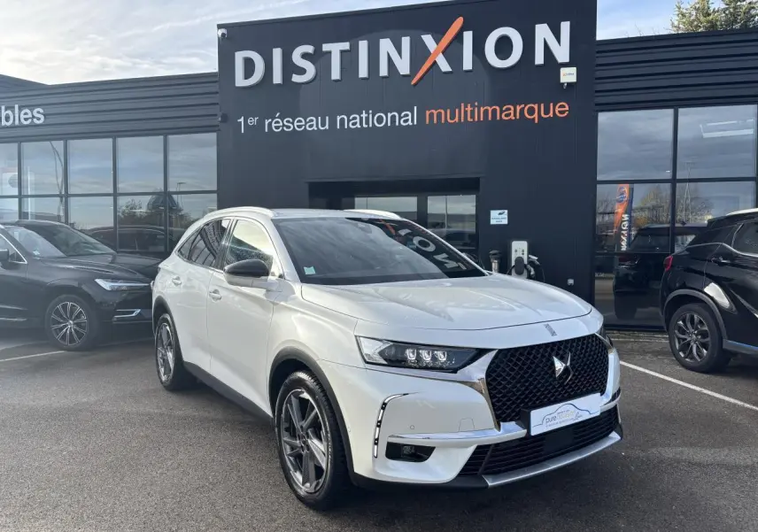 DS7 Crossback blanc en 3/4 avant droit avec calandre noire et jantes alliage, stationné devant un bâtiment Distinxion.