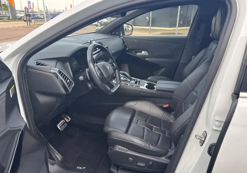 Intérieur côté conducteur du DS7 Crossback blanc 2021, sièges cuir noirs et tableau de bord moderne.