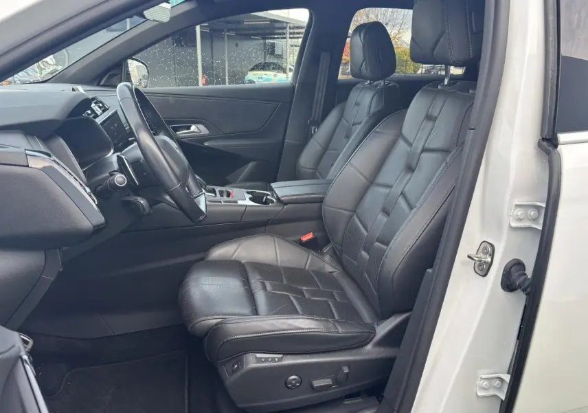Vue intérieure côté conducteur du DS7 Crossback blanc avec sièges avant en cuir noir et tableau de bord moderne.