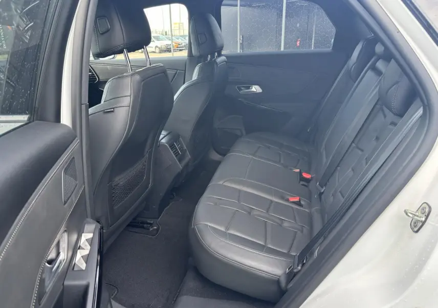 Vue côté gauche de l'habitacle arrière du DS7 Crossback blanc, avec sièges en cuir noir et finitions élégantes.
