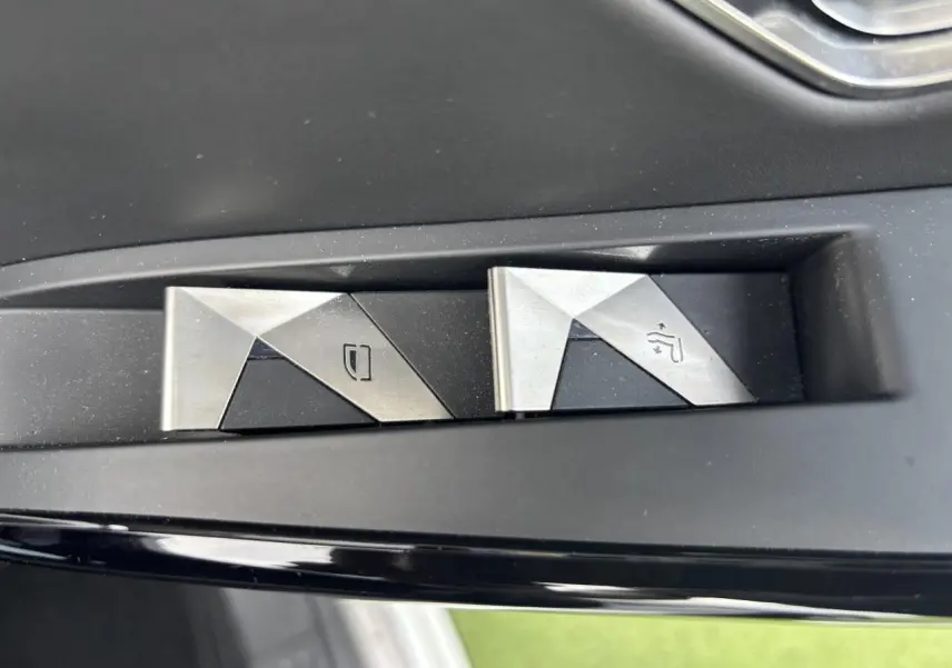 Boutons métalliques de commande des vitres sur la portière côté gauche d'un DS7 Crossback blanc de 2021.