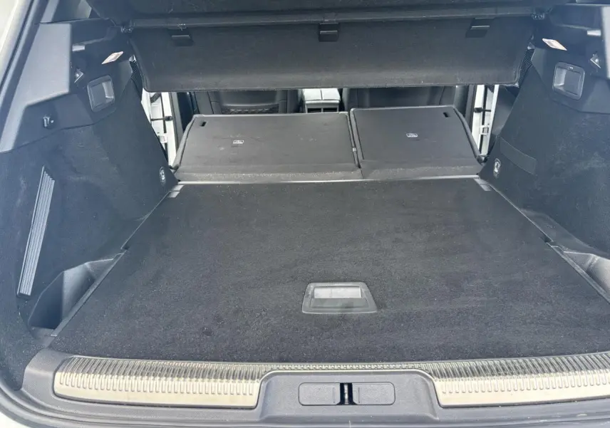 Coffre ouvert du DS7 Crossback blanc, banquette arrière rabattue, espace de chargement spacieux et revêtement noir.