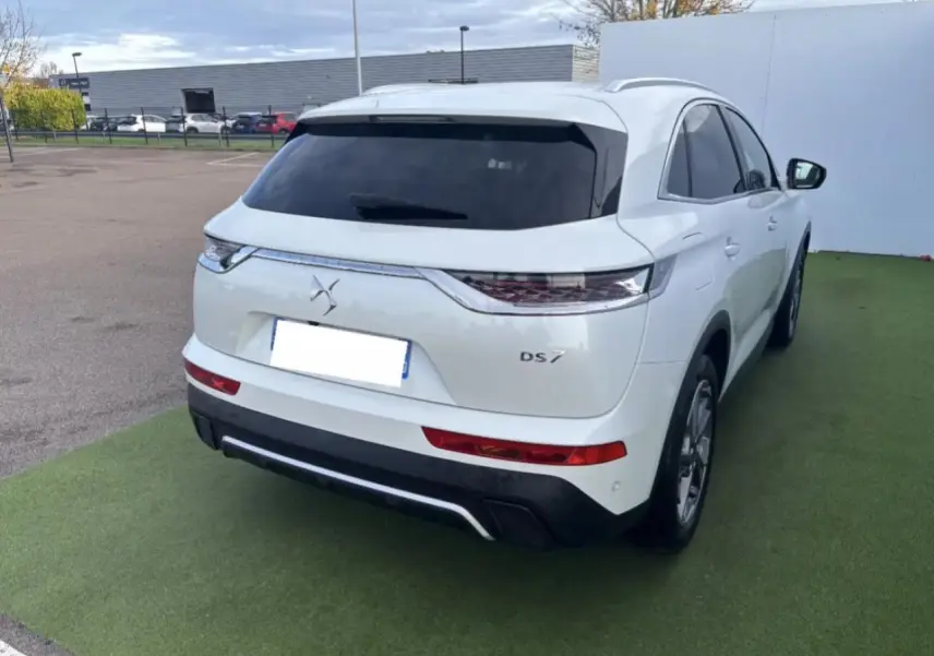 Vue 3/4 arrière droite d'un DS7 Crossback blanc nacré avec vitres arrière surteintées et feux arrière 3D écailles.