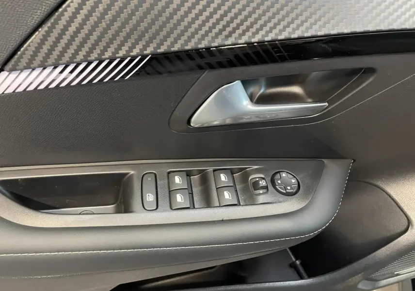 Détail de la porte avant gauche noire de la Peugeot 208 1.2i Hybrid avec commandes de vitres et rétroviseurs.