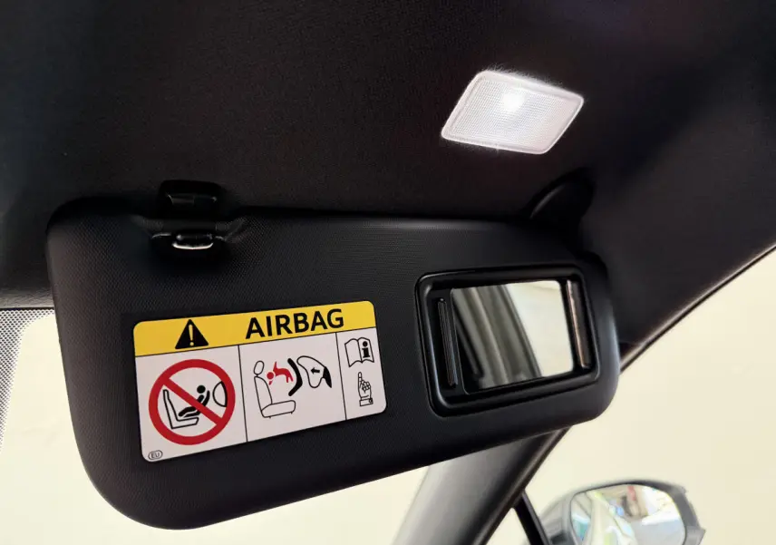Détail du pare-soleil côté conducteur noir avec miroir et avertissement airbag dans un Toyota C-HR blanc.