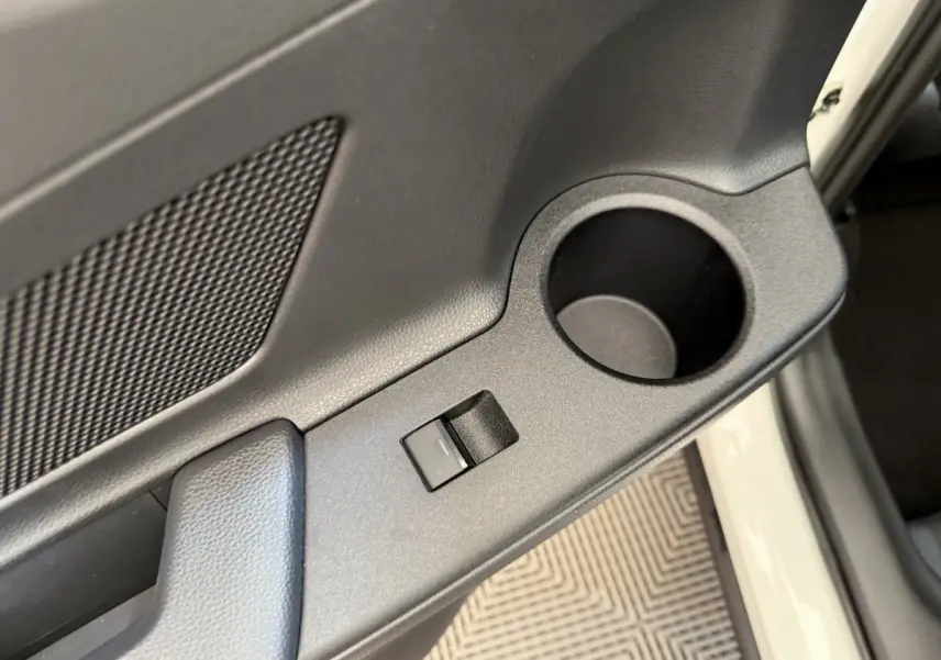 Gros plan sur la porte avant droite blanche du Toyota C-HR 2024, montrant la commande de vitre et un porte-gobelet intégré.