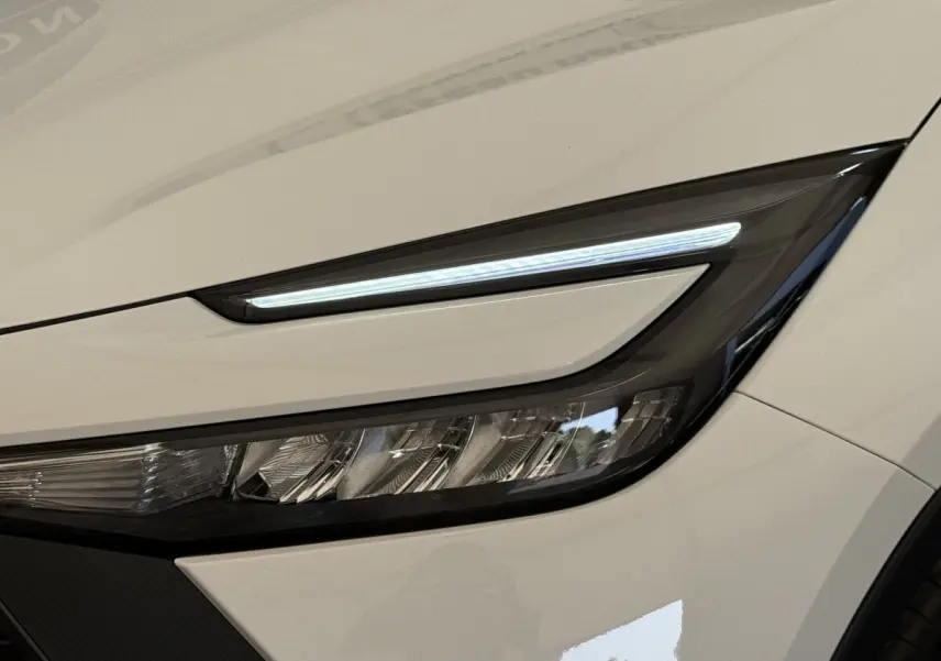Gros plan sur le phare avant droit blanc du Toyota C-HR 1.8 Hybride 140 Dynamic avec LED fine et design anguleux.