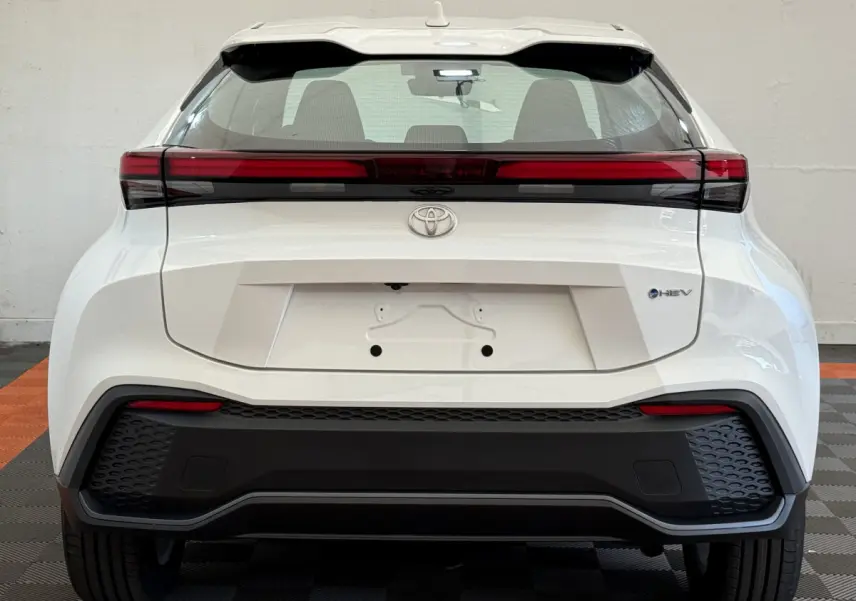 Vue arrière du Toyota C-HR 1.8 Hybride blanc 2024 avec feux arrière horizontaux et logo HEV visible.