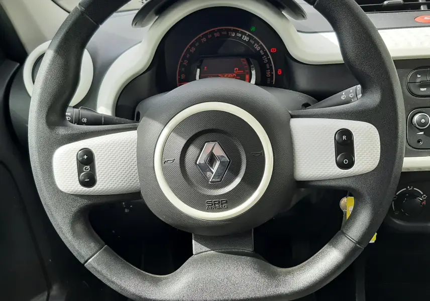 Vue rapprochée du volant noir et blanc de la Renault Twingo III 2021, avec tableau de bord numérique en arrière-plan.