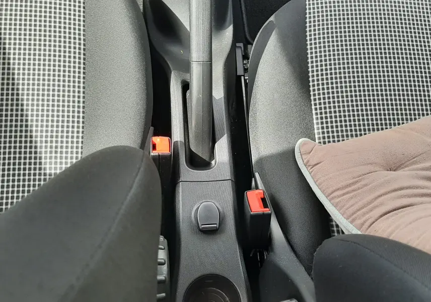 Vue plongeante sur la console centrale de la Renault Twingo III Life 2021, montrant frein à main et sièges tissu gris à motifs.