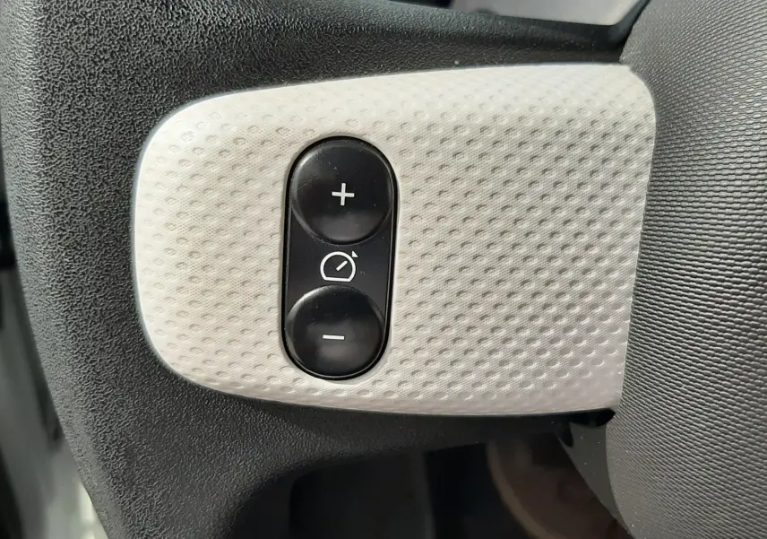 Gros plan sur les boutons de réglage des rétroviseurs sur le volant d’une Renault Twingo III blanc cristal.