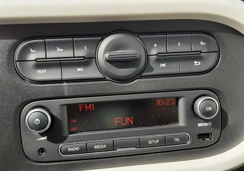 Gros plan sur la console centrale noire et blanche du Renault Twingo III blanc cristal, avec écran radio affichant "FUN".
