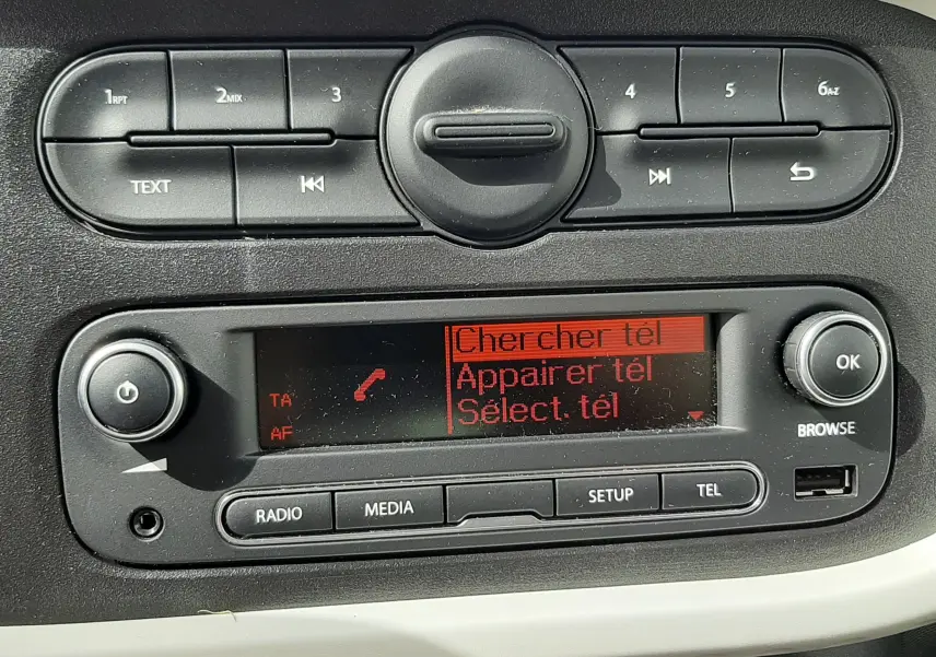 Détail de la console centrale de la Renault Twingo III blanche, affichant l’écran radio avec options de téléphone et commandes intégrées.