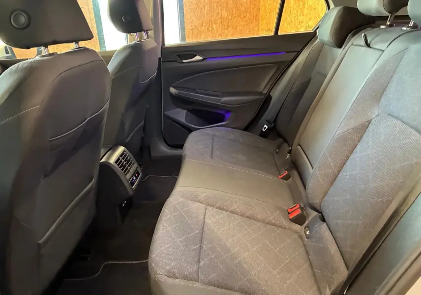 Vue intérieure arrière côté droit de la Volkswagen Golf 1.0 eTSI 110 DSG7 Life Plus 2023 avec sièges tissu gris et éclairage d'ambiance violet.