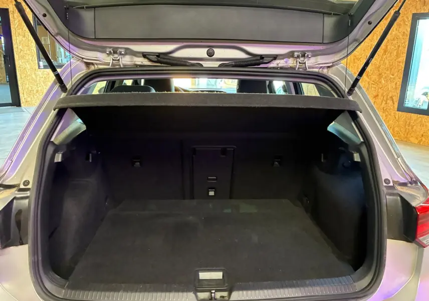 Coffre ouvert vu de l'arrière d'une Volkswagen Golf gris clair 2023, version 1.0 eTSI 110 DSG7 LIFE PLUS, intérieur noir.