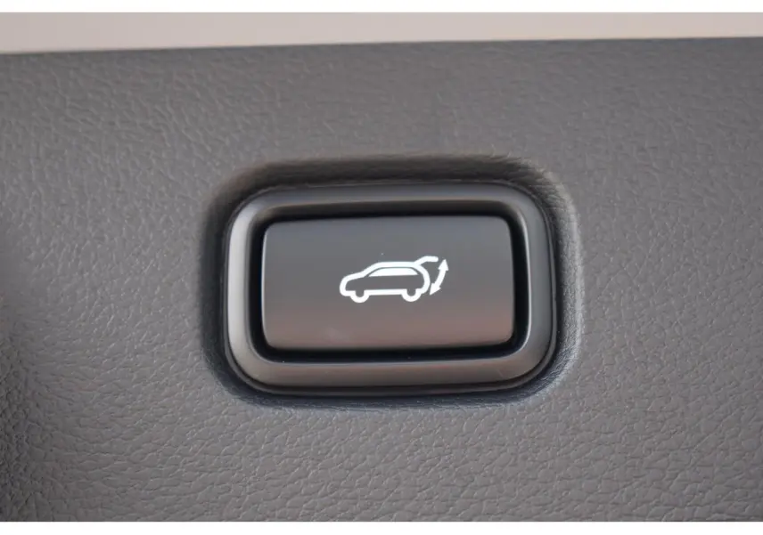 Bouton noir d'ouverture électrique du hayon sur tableau de bord d'un Kia Sportage gris 2026 hybride.