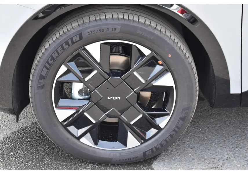 Gros plan sur la jante noire brillante 19 pouces Michelin du Kia Sportage hybride gris, avec logo KIA au centre.