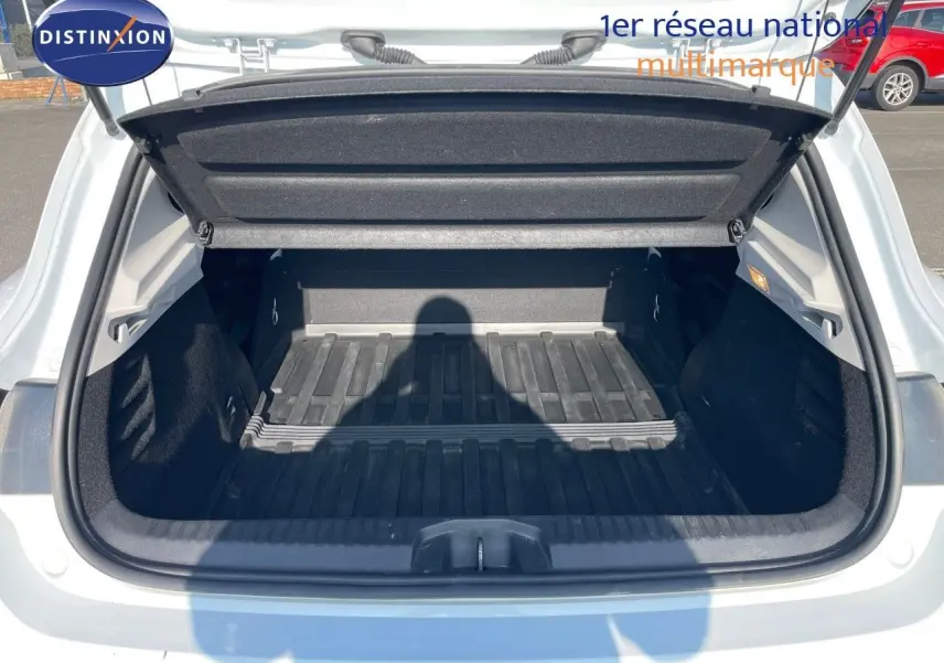 Coffre ouvert d'une Renault Clio Société blanc glacier, montrant l'espace de chargement vide et la trappe arrière relevée.