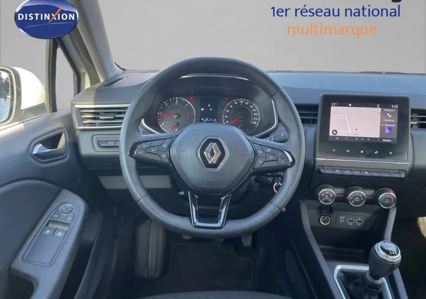 Vue intérieure centrée sur le volant Renault d'une Clio Société blanche, avec tableau de bord et écran tactile visible.