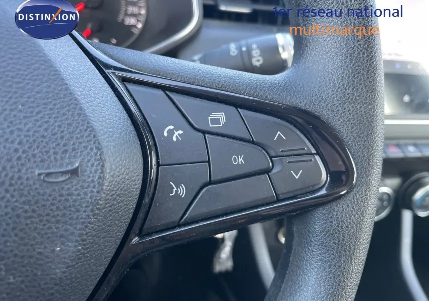 Gros plan sur les commandes multifonctions noires du volant d'une Renault Clio Société blanche Glacier, version 2020.