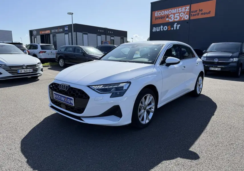Audi A3 Sportback blanc Arcona vue 3/4 avant droit avec jantes alliage 5 branches sur parking extérieur.