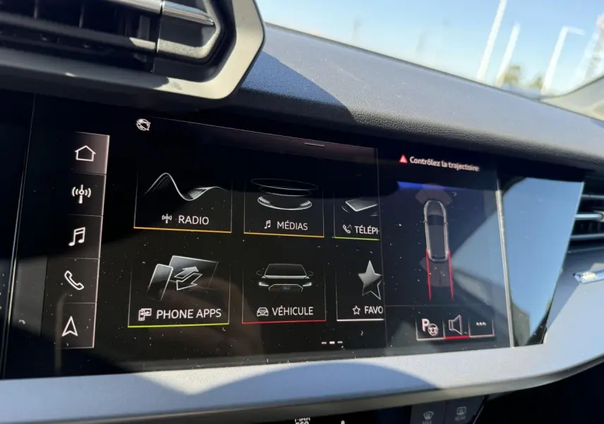 Écran tactile central de l'Audi A3 Sportback 2024 montrant l'interface multimédia et l'assistance au stationnement.
