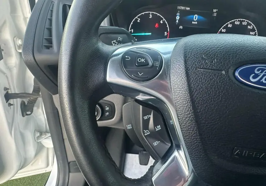 Vue rapprochée du volant multifonction noir du Ford Transit Connect blanc, avec tableau de bord digital en arrière-plan.