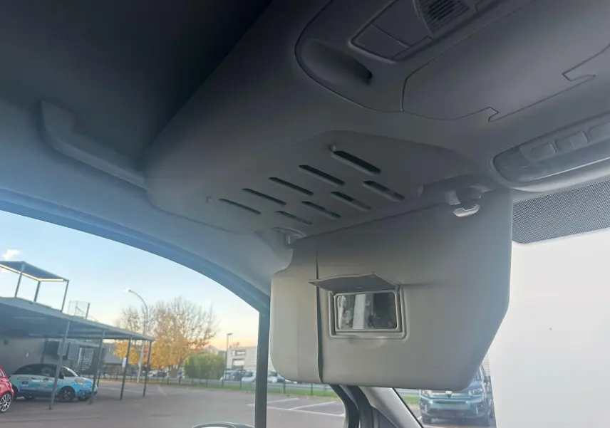 Vue intérieure côté conducteur du pare-soleil avec miroir intégré du Ford Transit Connect blanc stationné à l'extérieur.