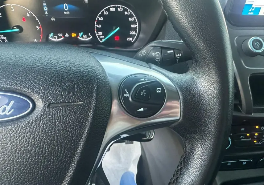 Gros plan sur le volant multifonction noir et le tableau de bord numérique du Ford Transit Connect blanc de 2019.