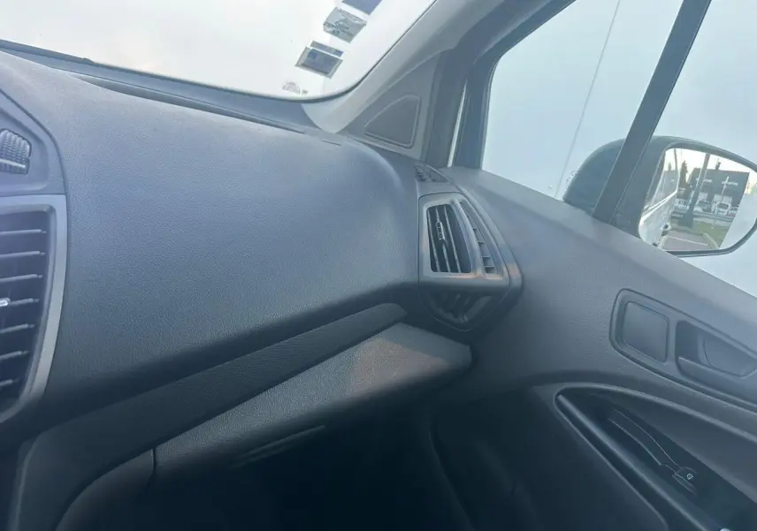 Vue intérieure côté passager du tableau de bord noir du Ford Transit Connect blanc avec aérateurs angulaires.