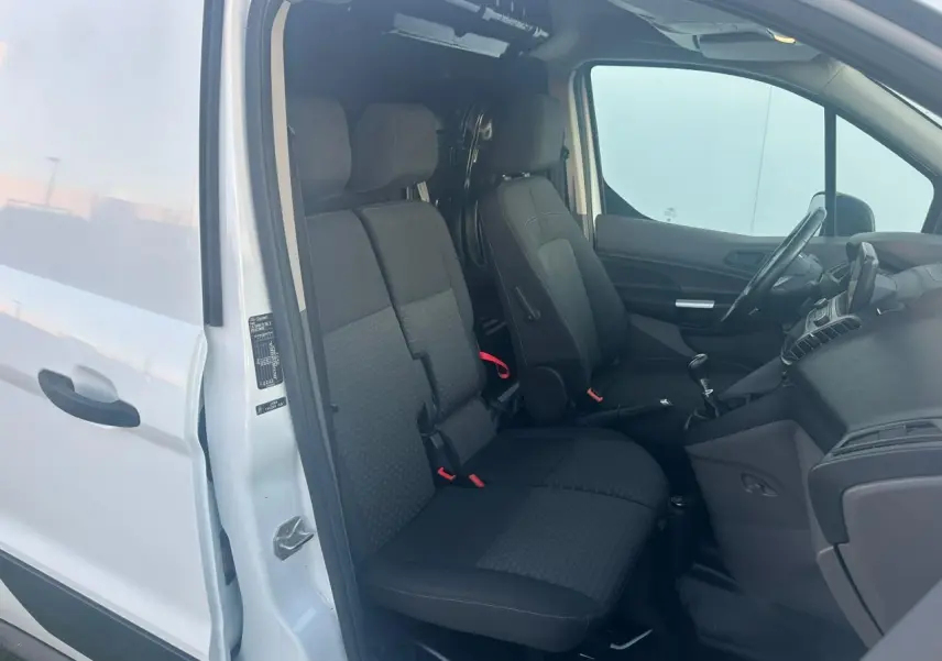 Vue intérieure côté conducteur du Ford Transit Connect blanc de 2019, montrant les sièges avant et le tableau de bord.
