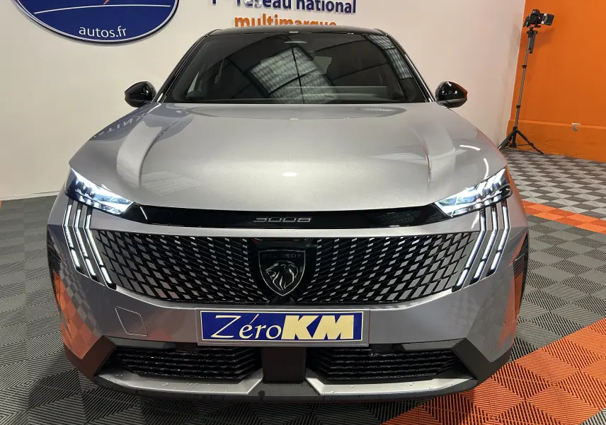 Vue de face du Peugeot 3008 III Hybrid gris Artense avec calandre noire et feux LED allumés en intérieur showroom.