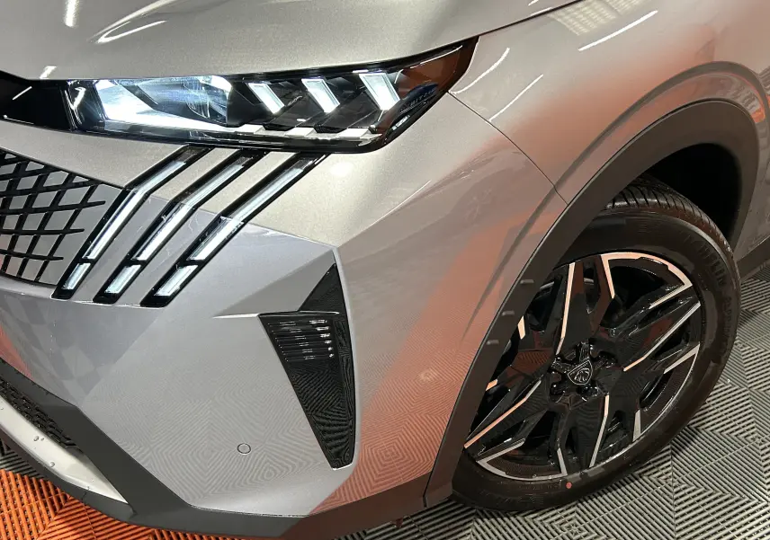 Gros plan sur l’avant droit du Peugeot 3008 gris Artense, mettant en valeur les phares LED et la jante noire brillante.