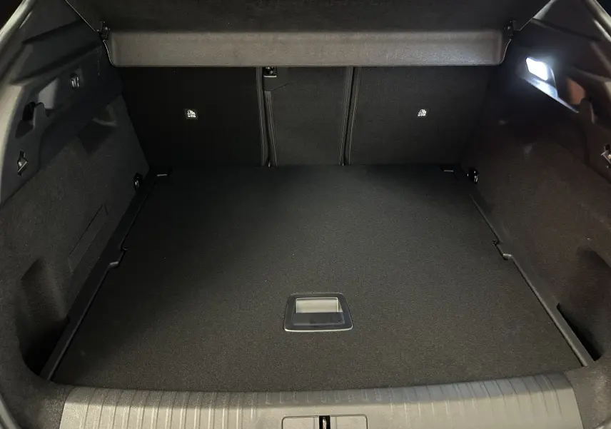 Vue intérieure du coffre spacieux et propre du Peugeot 3008 gris Artense, avec éclairage latéral et plancher plat.
