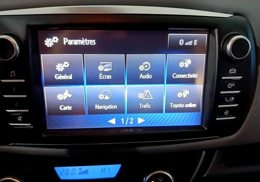 Écran tactile central en mode paramètres dans l'habitacle d'une Toyota Yaris blanche, vue de face rapprochée.