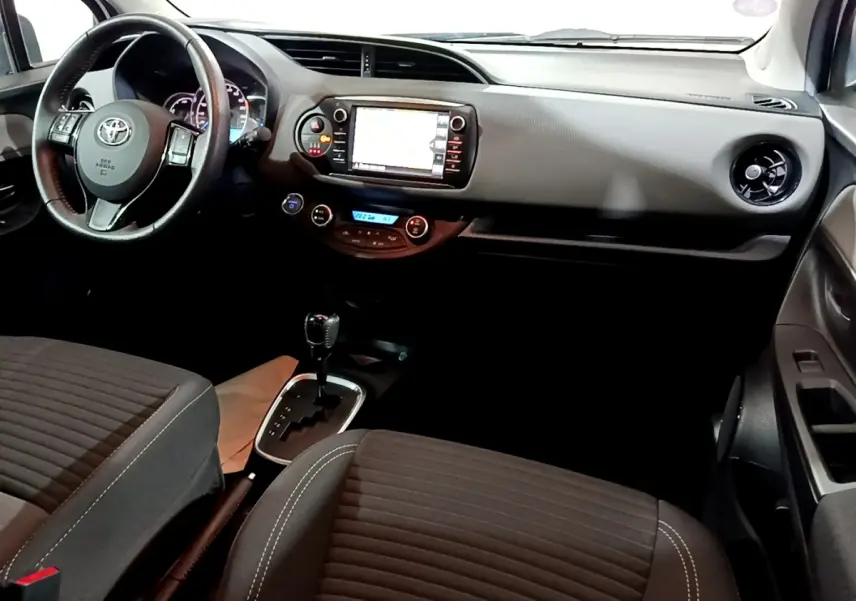Vue intérieure avant droite de la Toyota Yaris 1.5 Hybride 2020 avec tableau de bord noir et écran tactile central.