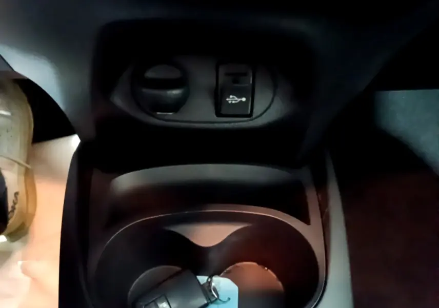 Gros plan sur la console centrale noire de la Toyota Yaris blanche 2020, avec prise USB et porte-gobelets.