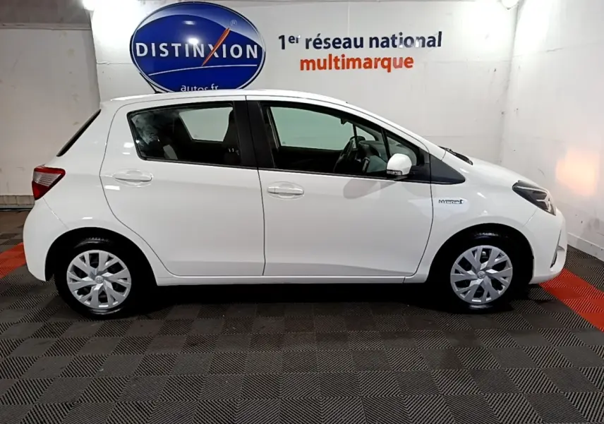 Profil droit d'une Toyota Yaris blanche 2020 hybride, avec jantes alliage et badge Hybrid visible sur l'aile avant.