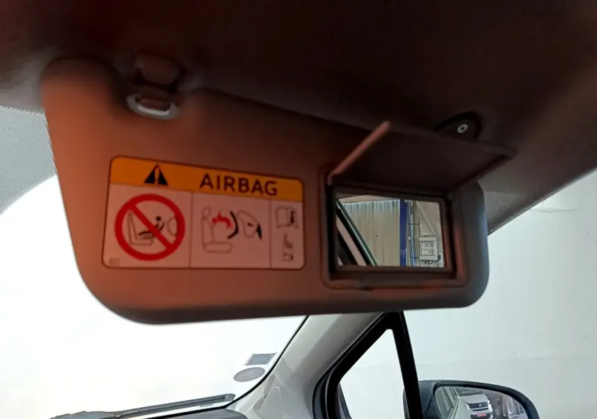 Détail du pare-soleil côté conducteur avec miroir et avertissement airbag dans l’habitacle d’une Toyota Yaris blanche.