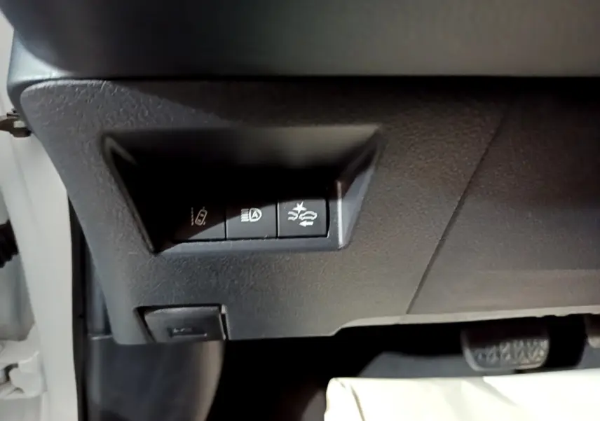 Gros plan sur les boutons de commande sous le tableau de bord d'une Toyota Yaris blanche, côté conducteur.