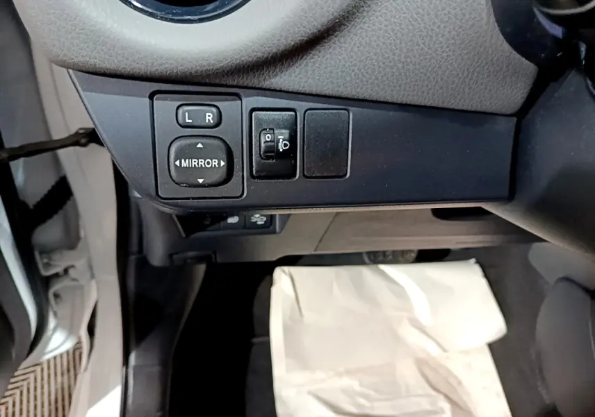 Vue rapprochée du tableau de bord côté gauche de la Toyota Yaris blanche, avec commandes réglage des rétroviseurs.