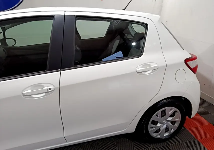 Vue latérale droite d'une Toyota Yaris blanche 2020, mettant en valeur les portes arrière et la roue arrière.