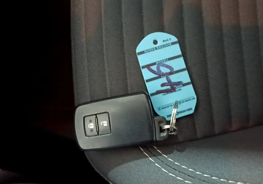 Télécommande noire de démarrage sans clé posée sur un siège tissu gris foncé à surpiqûres blanches, intérieur Toyota Yaris 2020.