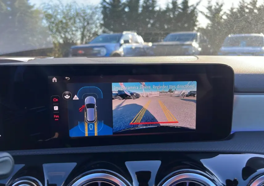 Écran central de la Mercedes Classe A 200D noir cosmos montrant la caméra de recul et l’aide au stationnement.