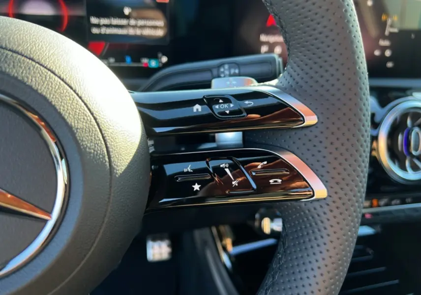 Gros plan sur le volant cuir perforé de la Mercedes Classe A 200D 2026 avec commandes multifonctions et tableau de bord numérique.