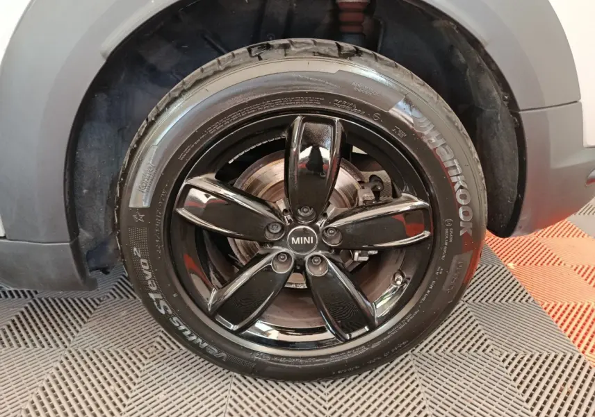 Gros plan sur la roue avant droite d'une MINI Countryman gris foncé avec jante noire brillante à cinq branches.