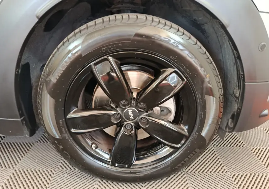 Gros plan sur la roue avant droite gris foncé du MINI Countryman avec jante noire brillante à cinq branches.