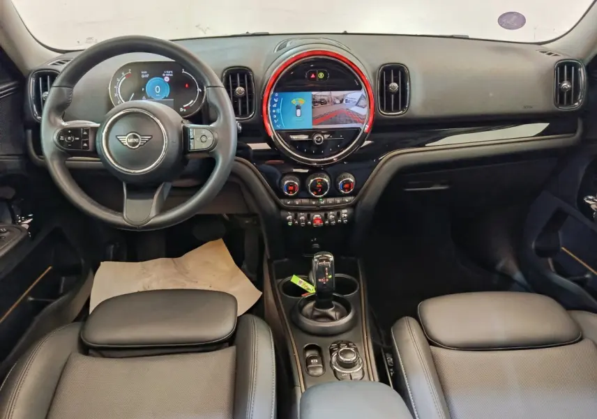 Vue intérieure avant du tableau de bord et volant cuir noir du MINI Countryman Cooper 2023 avec écran tactile central lumineux.