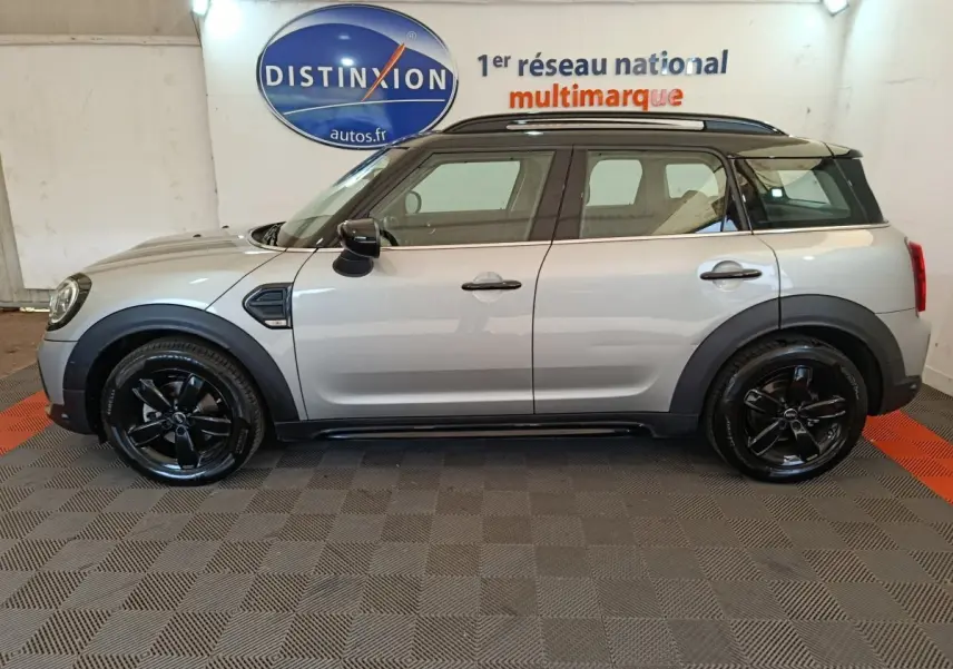 Vue de profil côté gauche d'une MINI Countryman gris foncé avec jantes noires et toit noir dans un showroom.