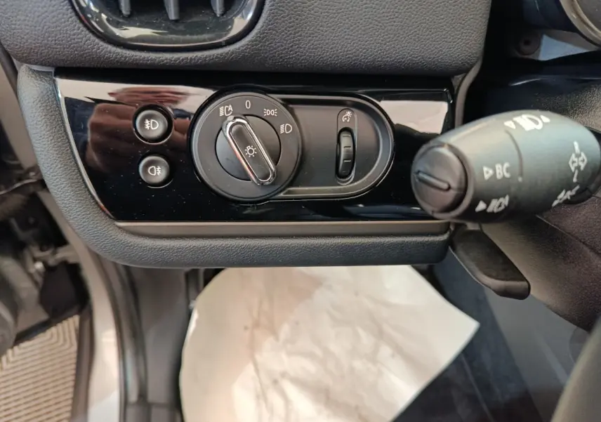 Gros plan sur la commande des phares et clignotants côté gauche du tableau de bord du MINI Countryman gris foncé 2023.